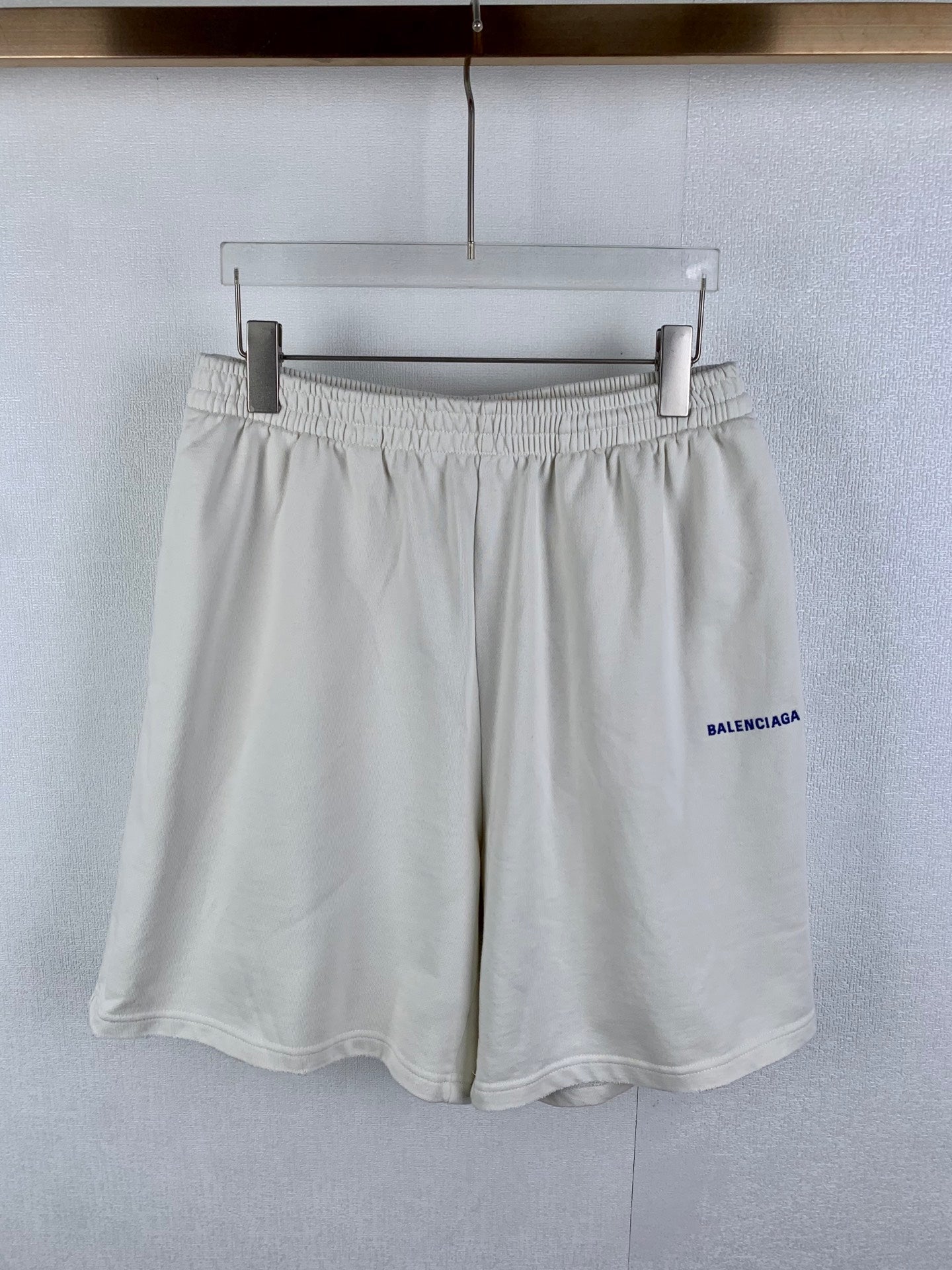 White elastic-waist shorts with pleated front and blue BALENCIAGA logo on side