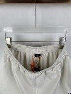 White shorts interior with elastic waistband, black label, and orange drawstring