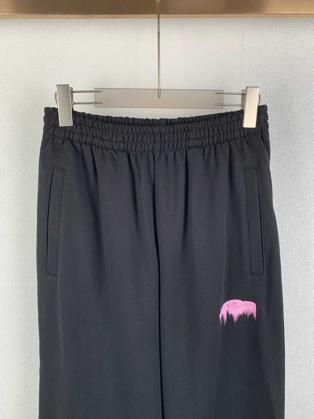 Balenciaga black pants front view with elastic waistband, side pockets, pink logo