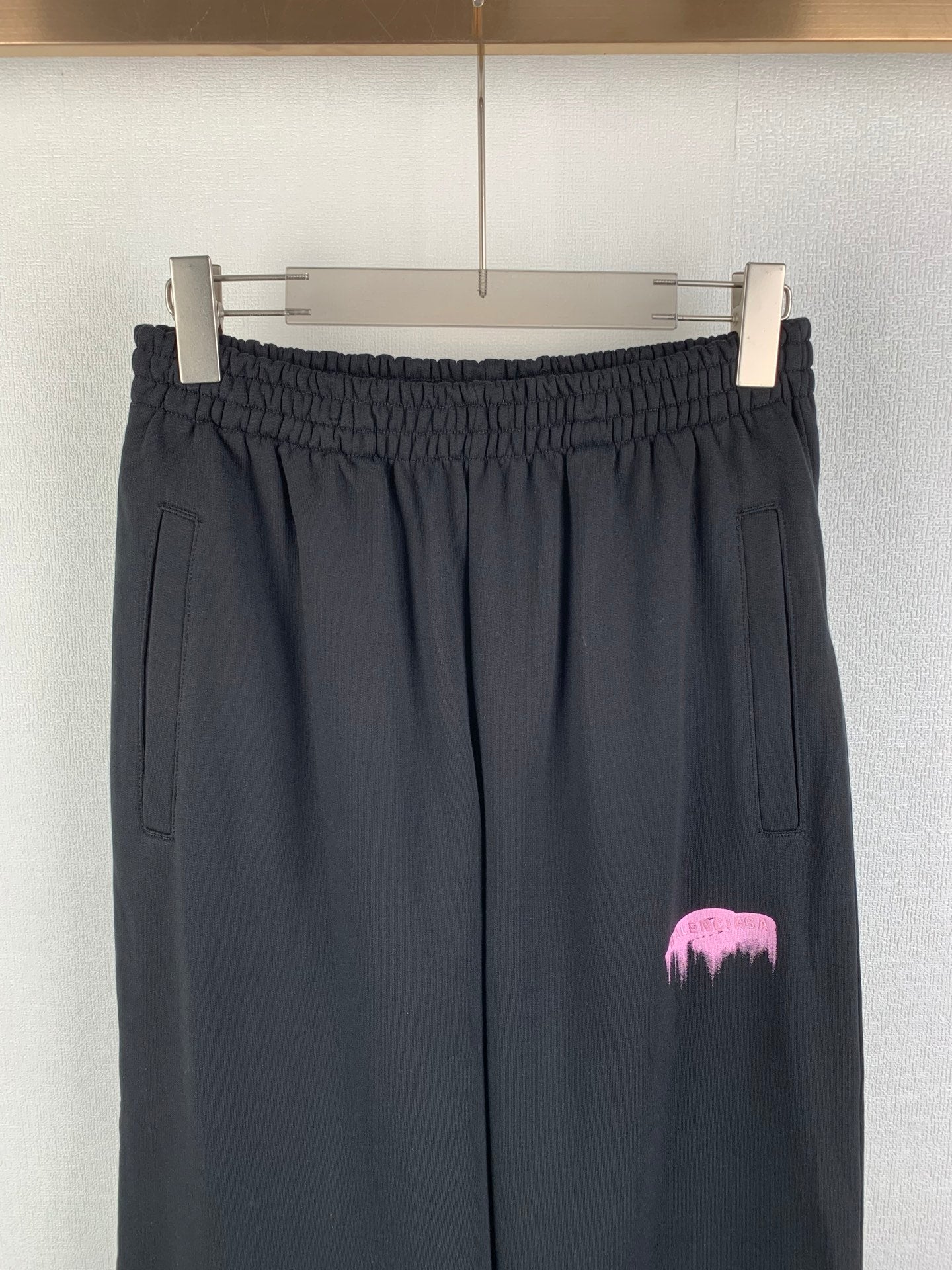 Balenciaga black pants front view with elastic waistband, side pockets, pink logo