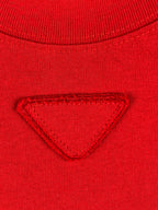 Red knit T-shirt chest with triangular embossed/embroidered emblem.