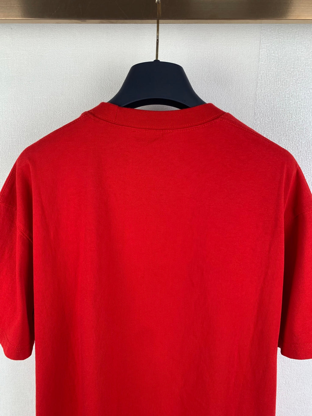 Red short-sleeve T-shirt back view, smooth fabric on hanger.