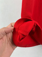 Red short-sleeve T-shirt cuff hem detail, fabric fold and stitched edge.