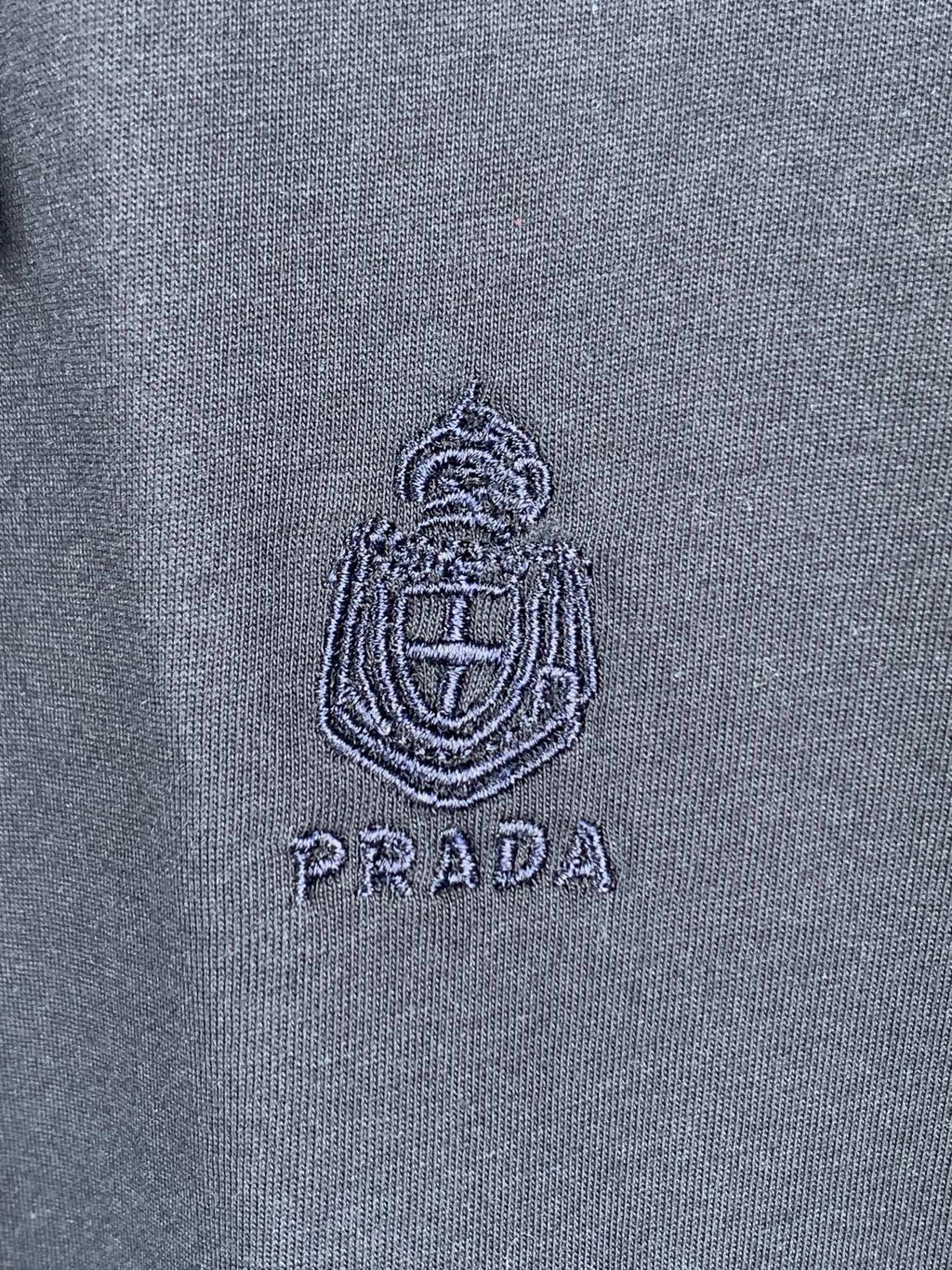 Embroidered Prada logo crest on navy T-shirt fabric