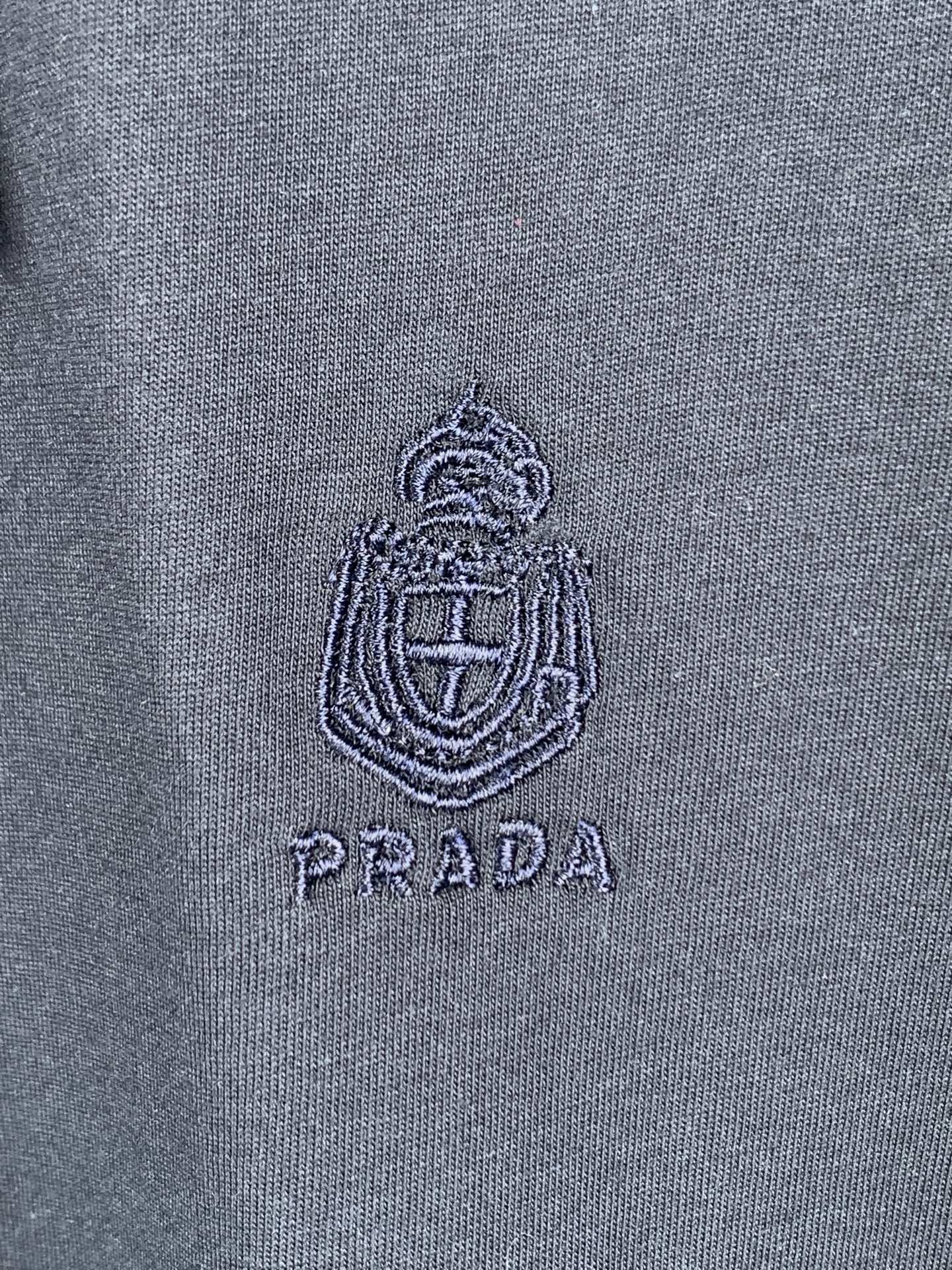 Embroidered Prada logo crest on navy T-shirt fabric