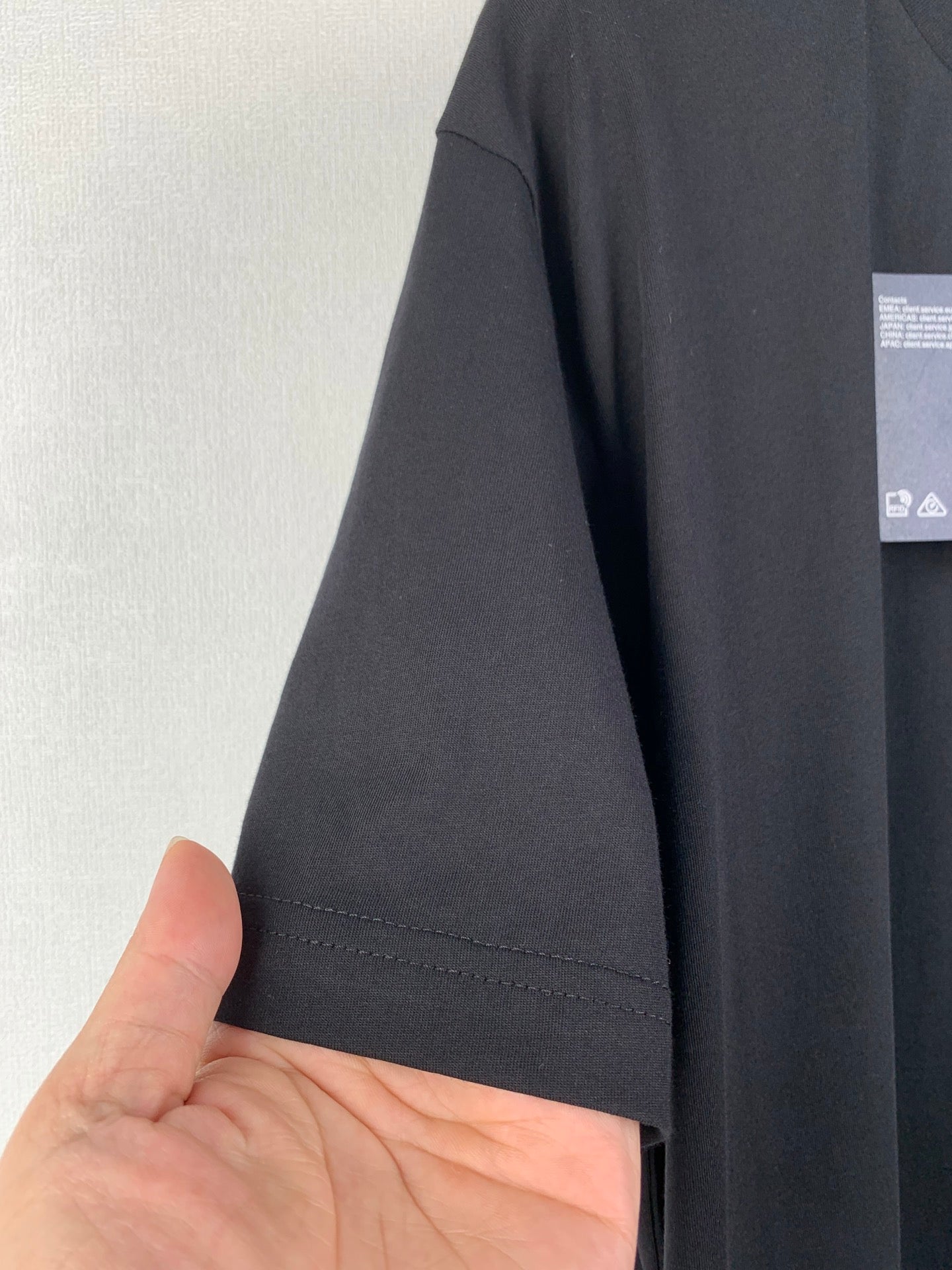 Prada T-shirt sleeve and hem in dark fabric with visible stitching