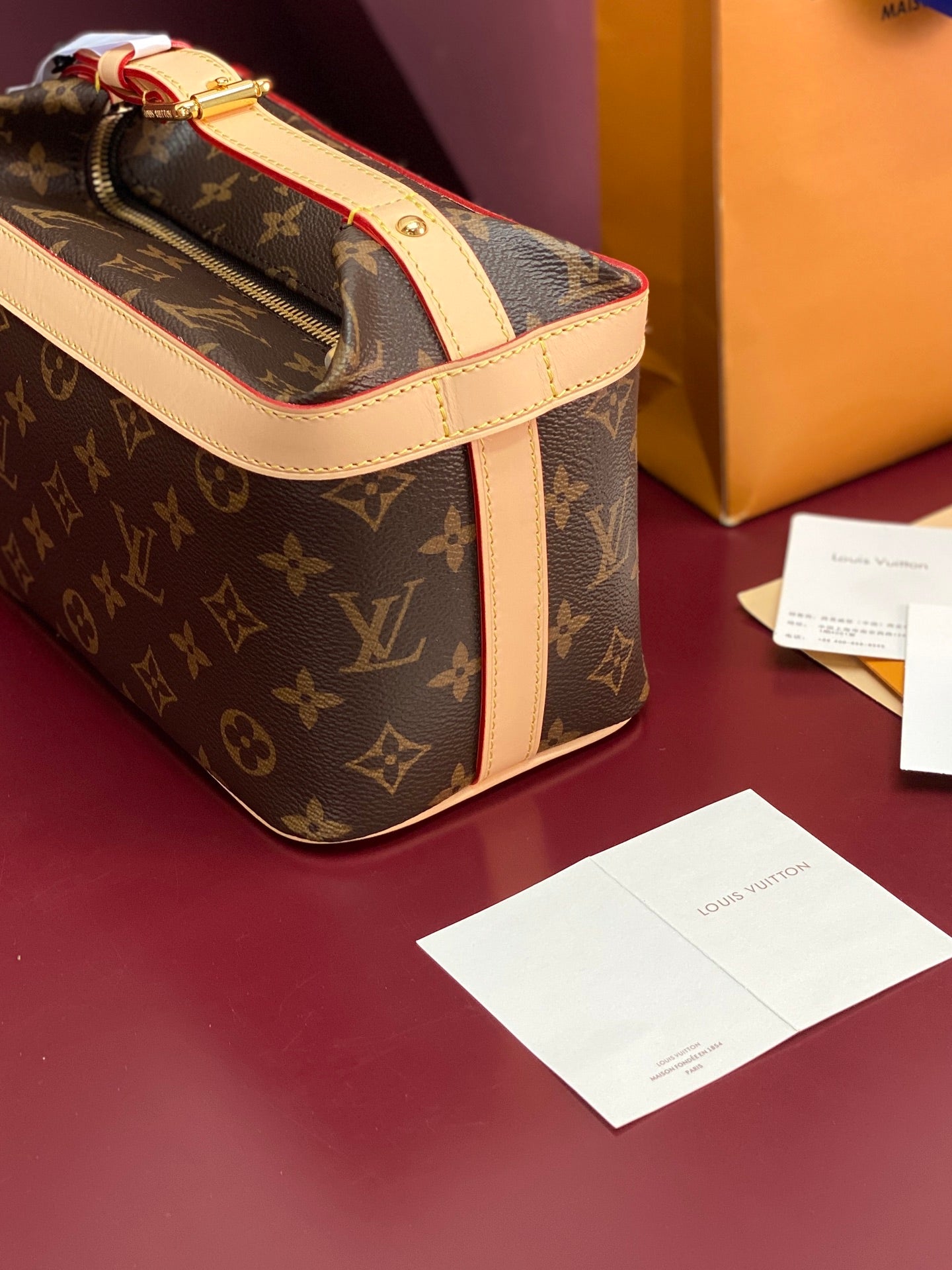 Louis Vuitton monogram bag side view with cream strap, gold zipper pull