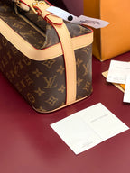 Louis Vuitton monogram bag with cream handles and attached tag, gold zipper hardware