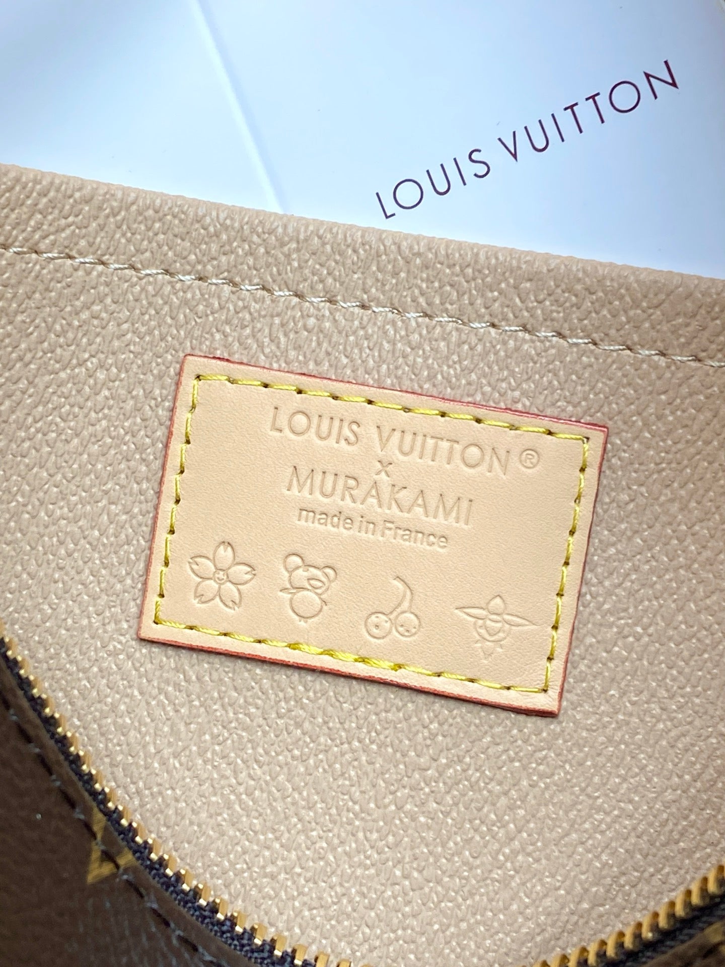 Louis Vuitton label on beige lining reading “AMURAKAMI”, stitched with floral icons