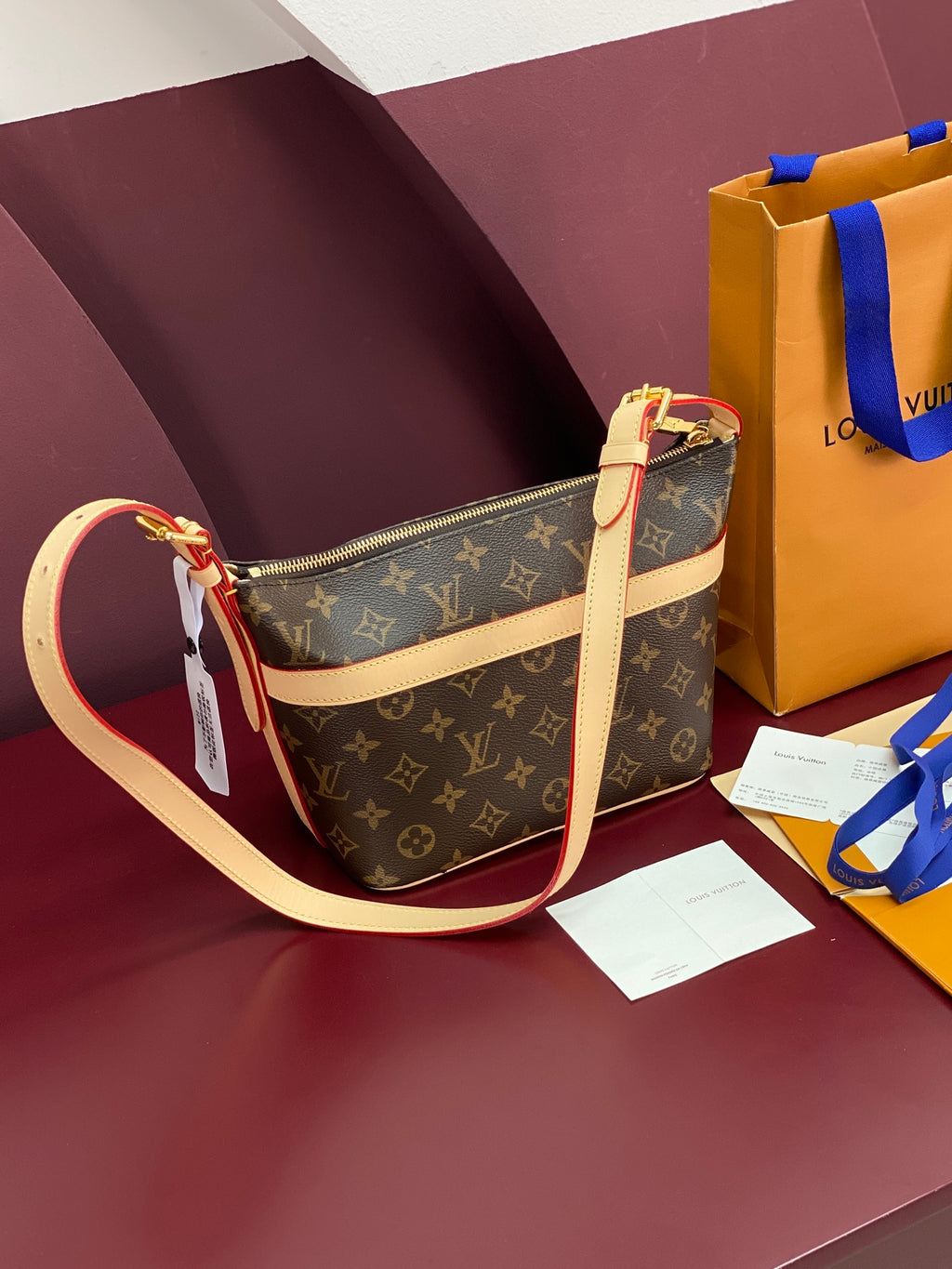 Louis Vuitton monogram shoulder bag with beige crossbody strap and zip top