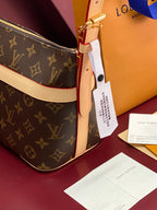 Louis Vuitton monogram bag with beige strap, gold hardware, and hanging tag