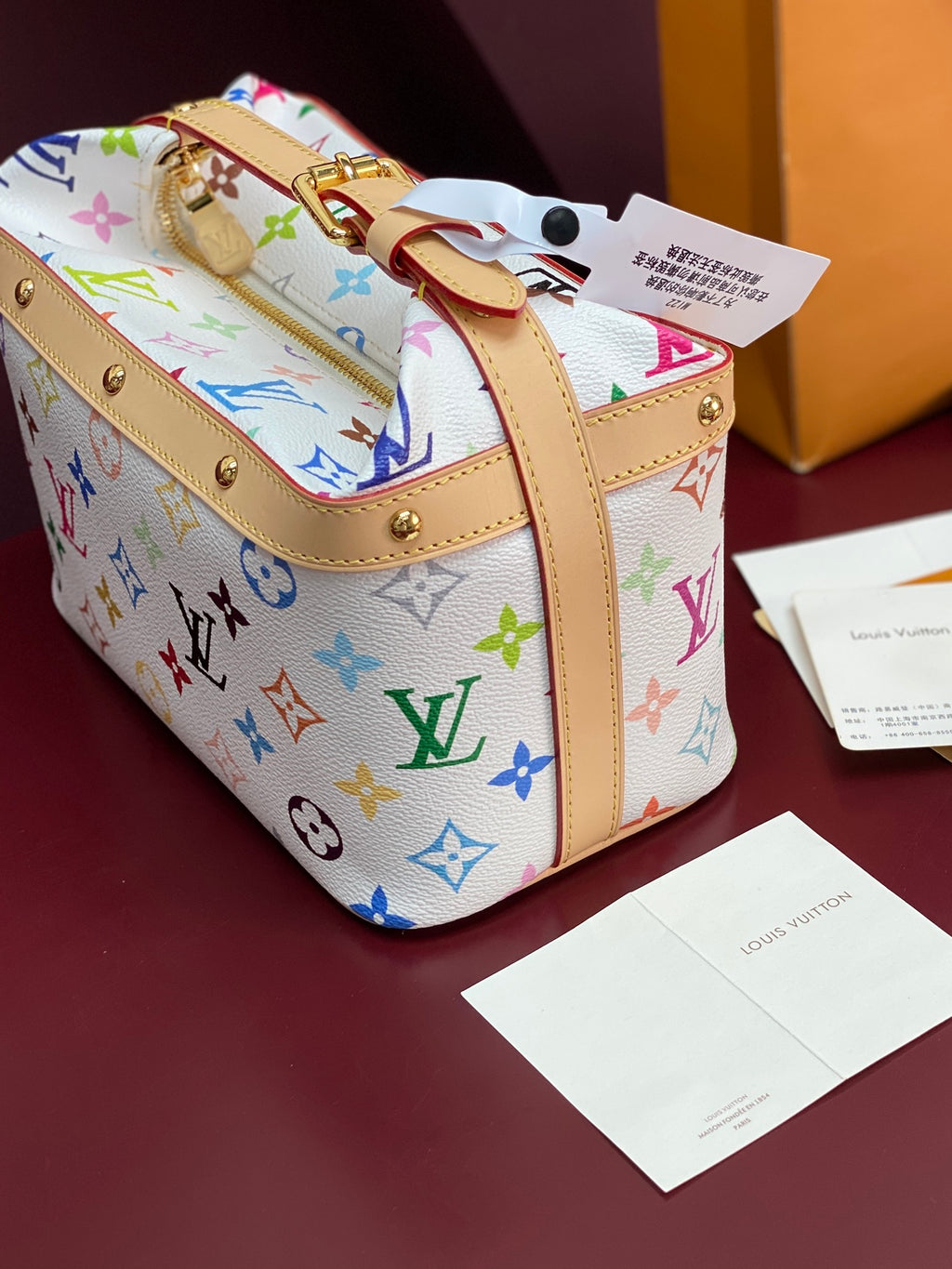 Louis Vuitton mini handbag with multicolor monogram print, tan straps and gold eyelets
