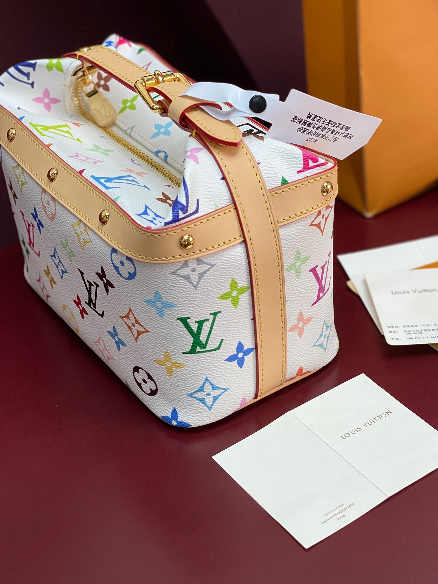 Louis Vuitton mini handbag with multicolor monogram print, tan straps and gold eyelets