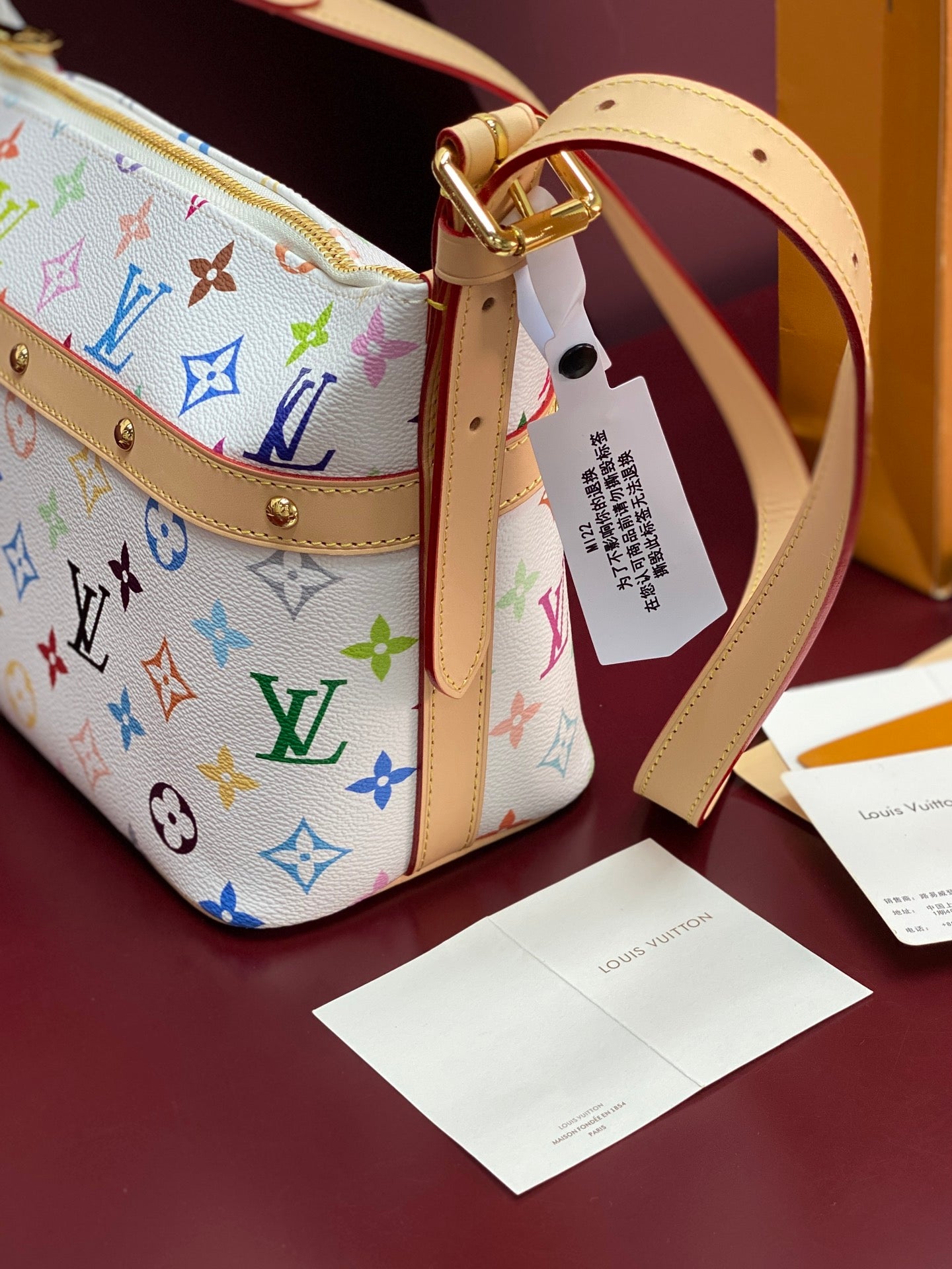 Louis Vuitton handbag exterior with gold buckle, multicolor monogram print, and tag