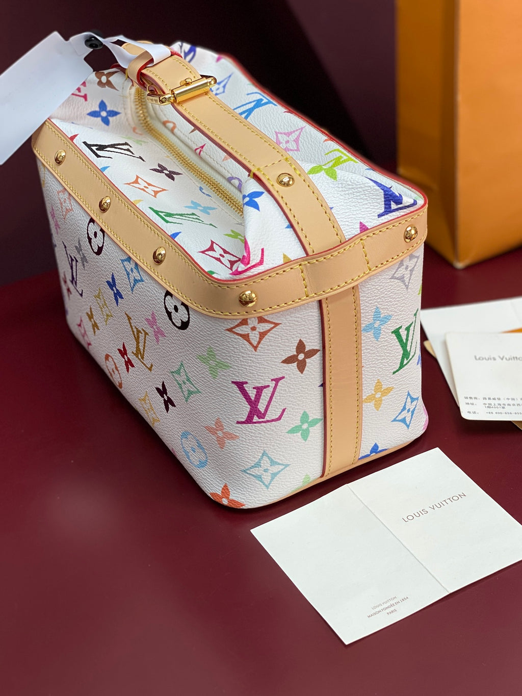 Louis Vuitton mini handbag with multicolor monogram print and tan top strap hardware