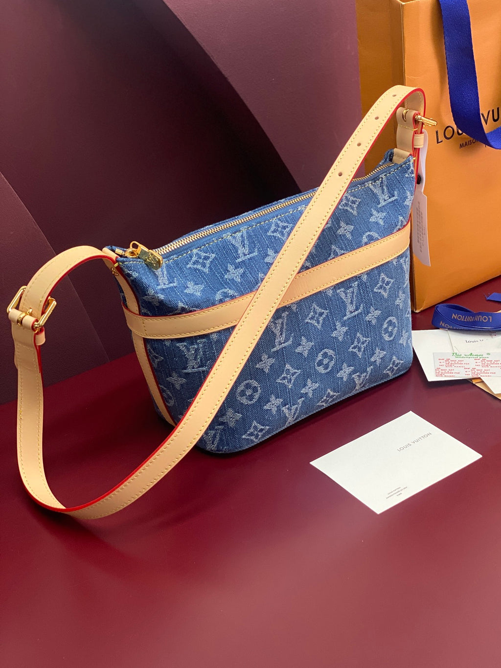 Louis Vuitton blue monogram crossbody bag with tan leather strap and gold zipper