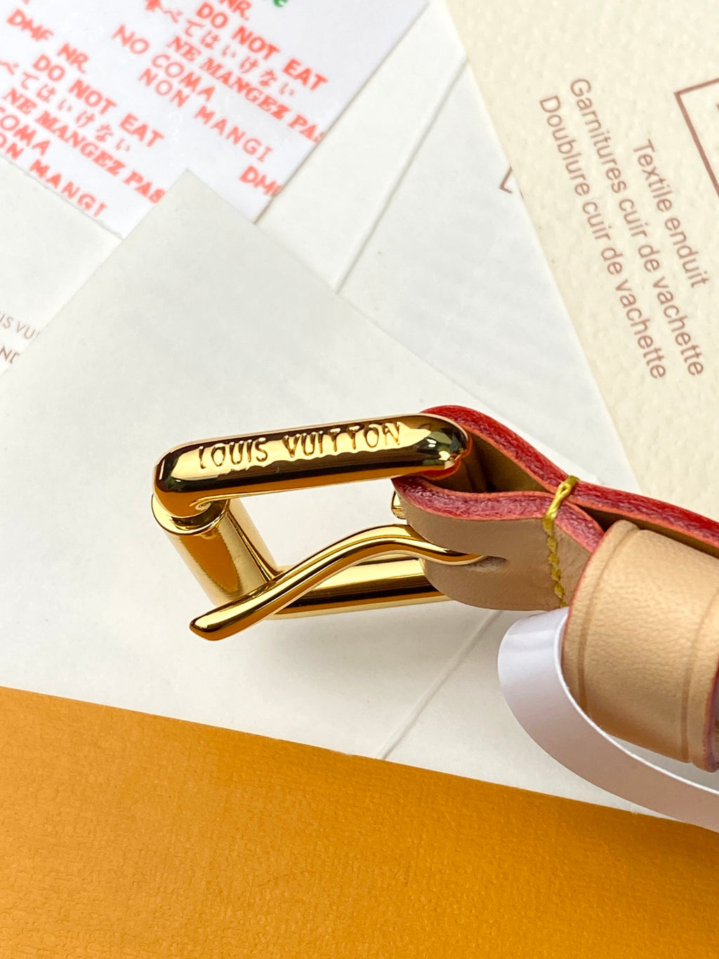 Louis Vuitton gold clasp with red and tan leather strap on bag