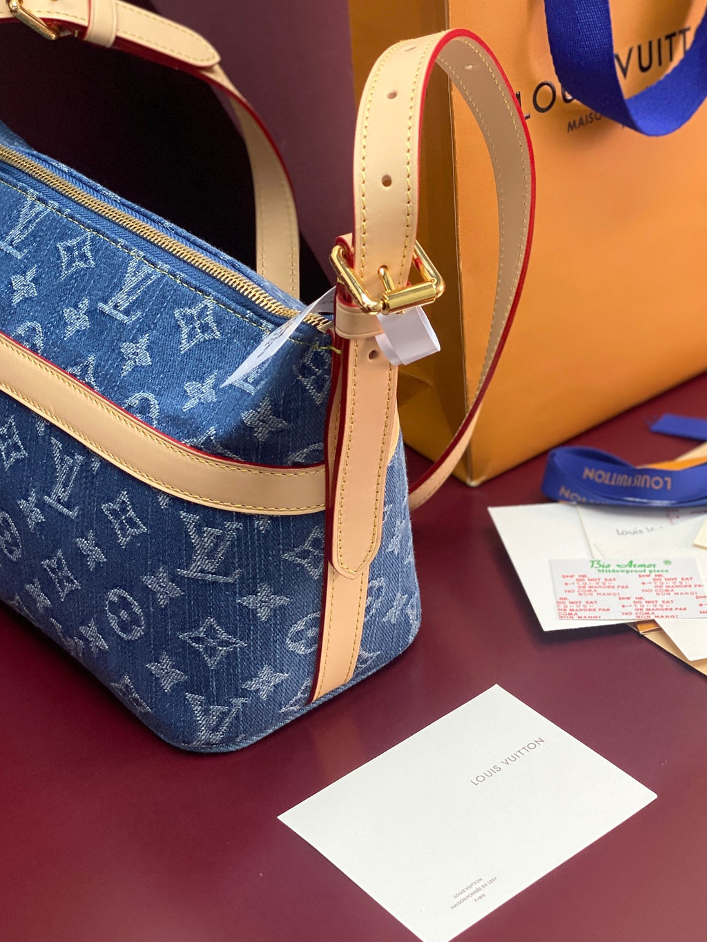 Louis Vuitton blue monogram bag with tan strap and gold buckle hardware detail