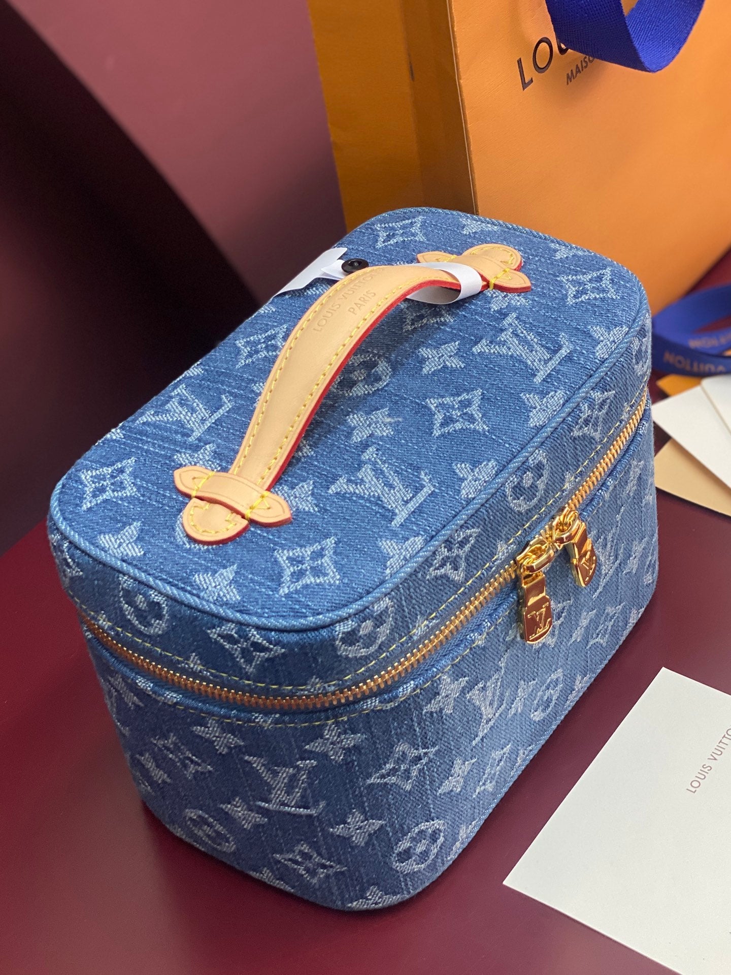 Louis Vuitton blue monogram vanity bag with tan handle and gold zipper trim