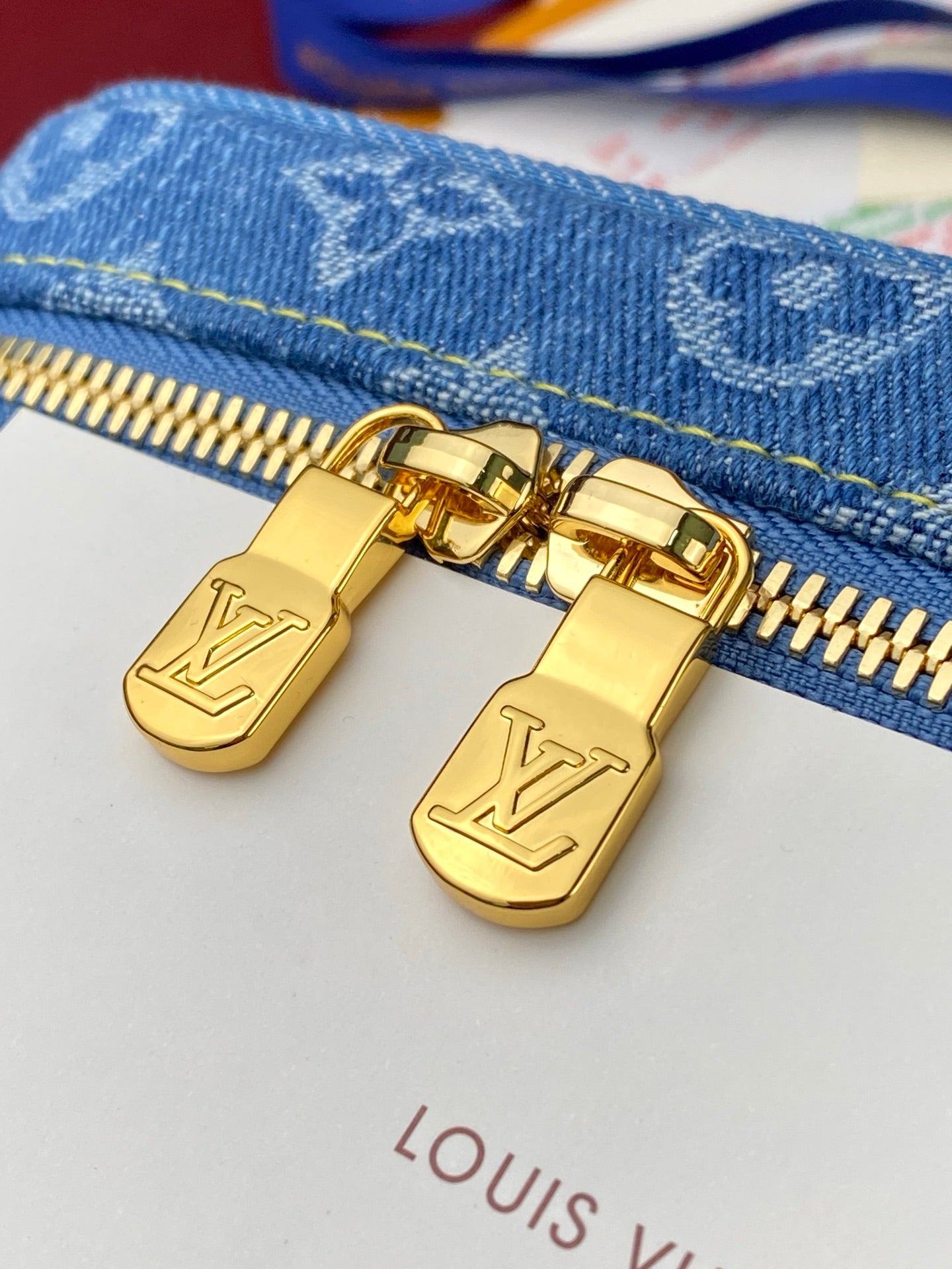 Louis Vuitton denim bag with gold zipper pulls and LV logo on hardware