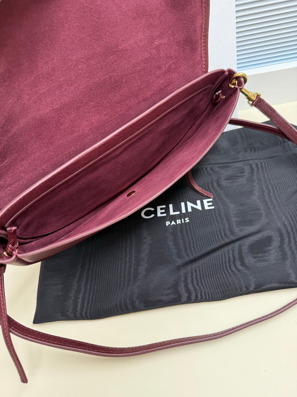 Celine shoulder bag side view with burgundy suede interior and crossbody strap