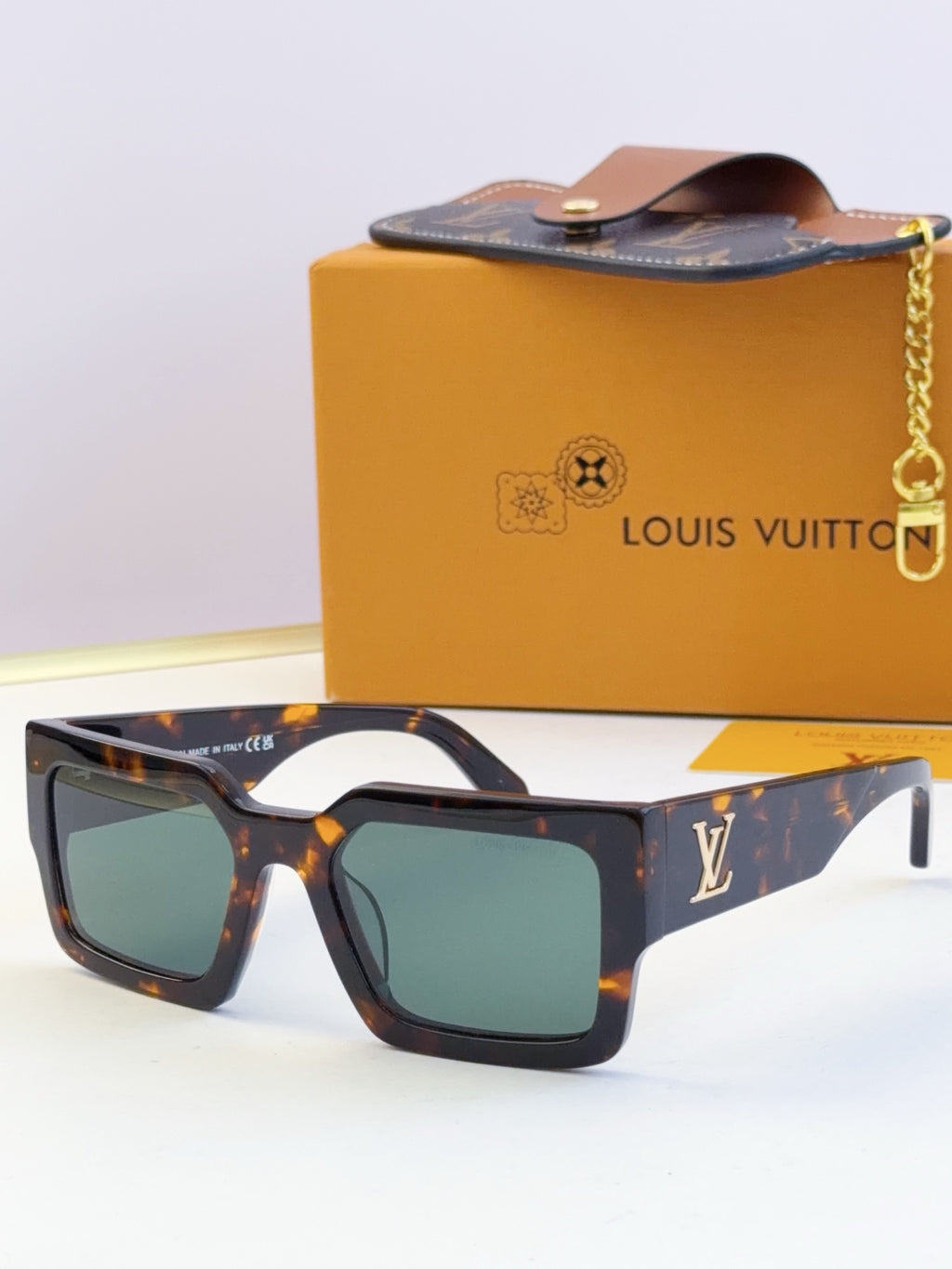 Louis Vuitton sunglasses with tortoiseshell frames and green-tinted lenses, LV logo on temple.