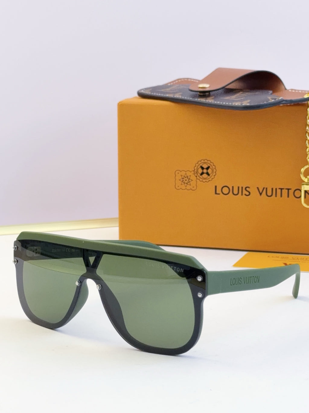 Green tinted sunglasses with dark frame and logo text on the temple