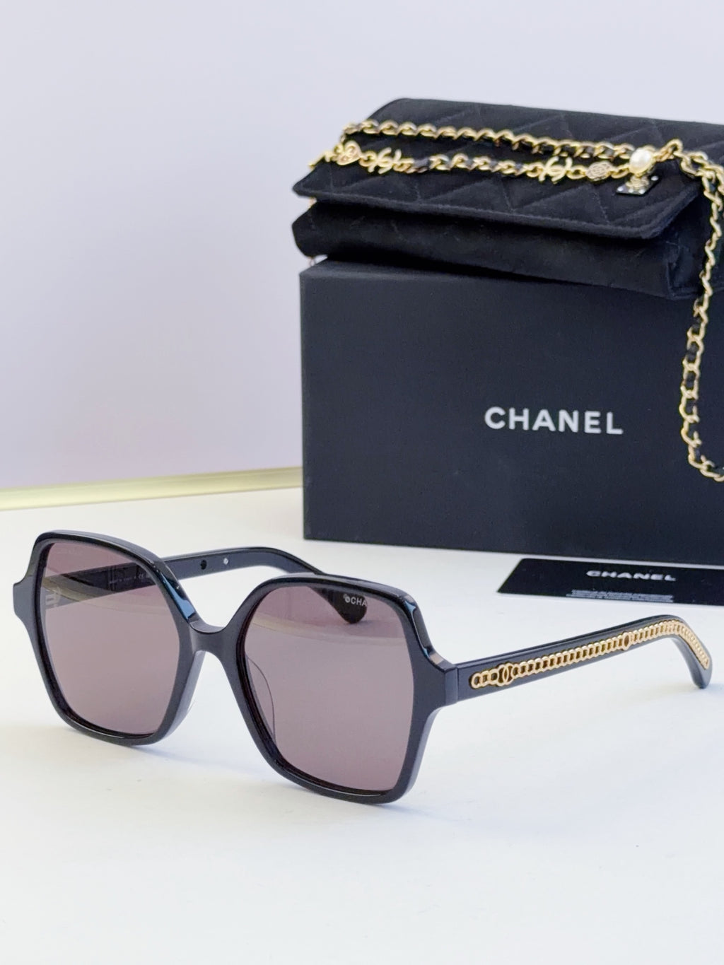 Chanel dark blue square sunglasses with purple-tinted lenses and gold chain detail