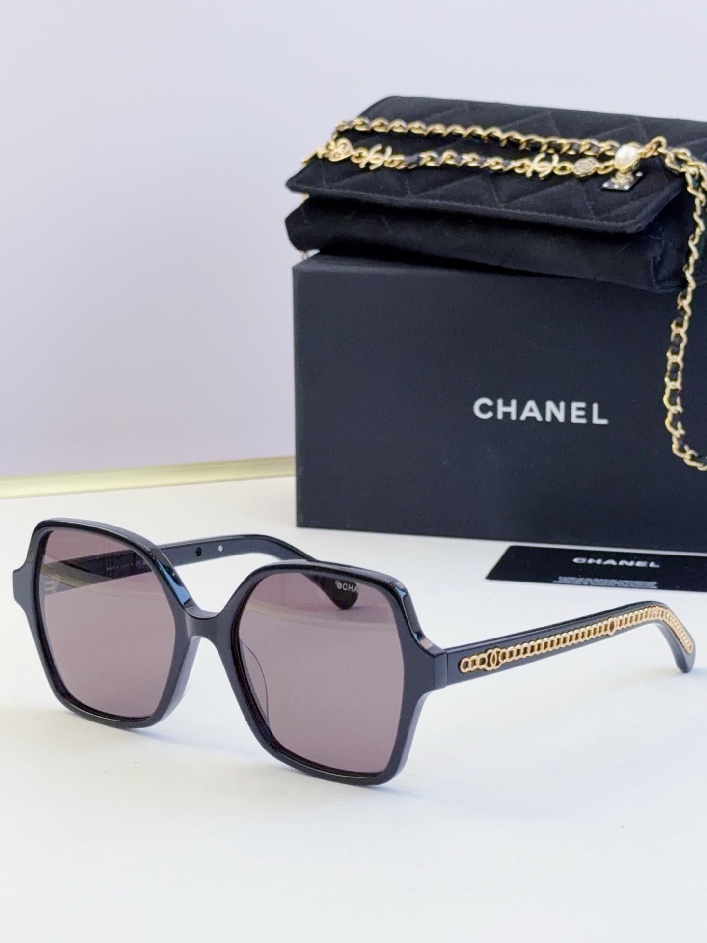 Chanel dark blue square sunglasses with purple-tinted lenses and gold chain detail