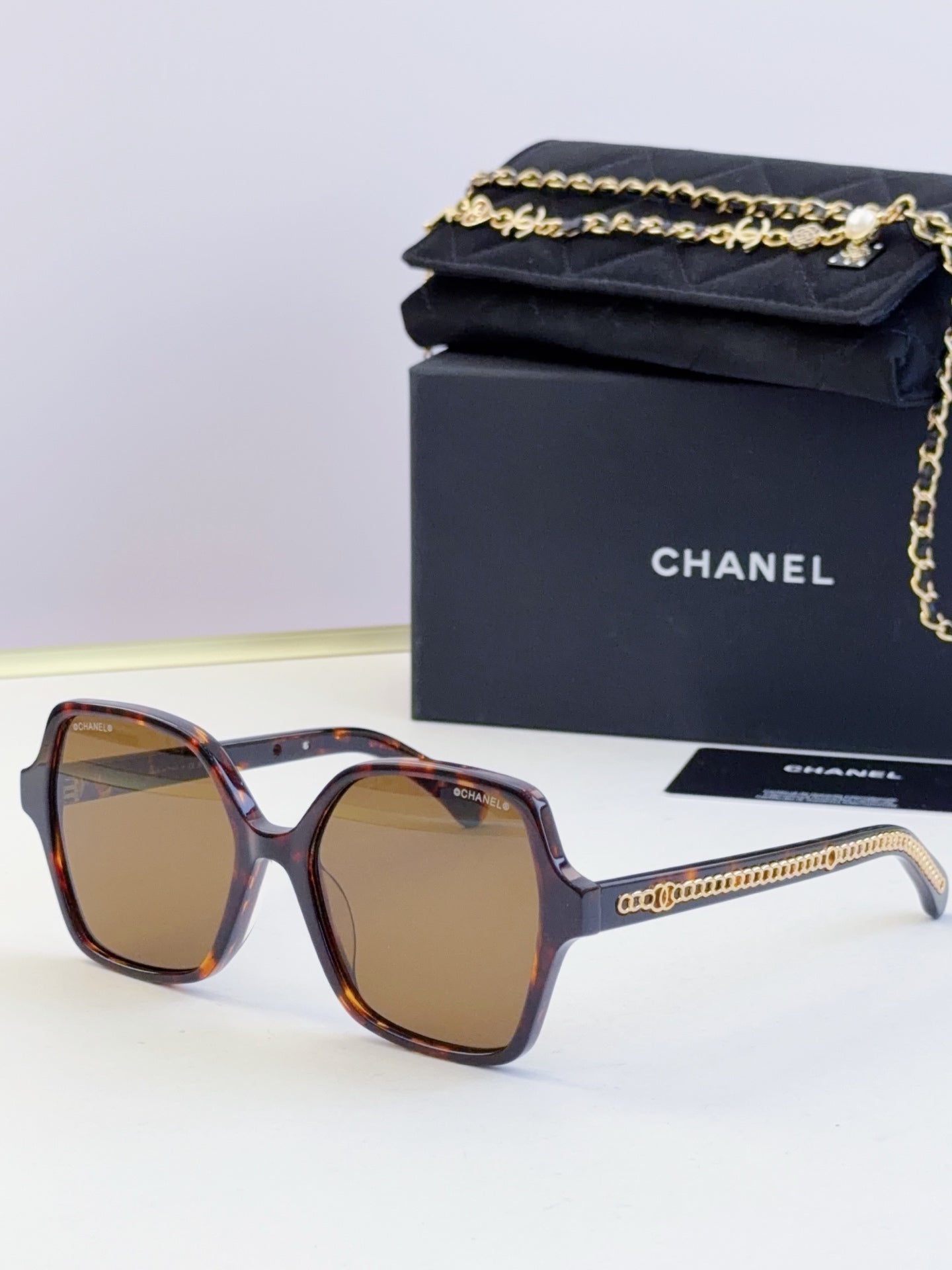 Chanel tortoiseshell square sunglasses with amber lenses and gold chain on arms