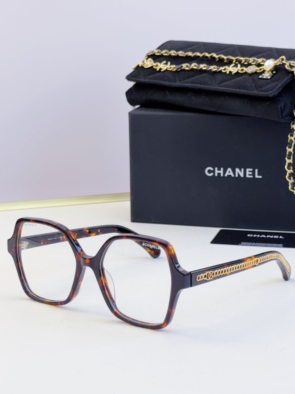 Chanel tortoiseshell square glasses with clear lenses and gold chain detail on arms