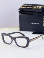 Gray glasses with oversized square frames, clear lenses, and gold chain on temples
