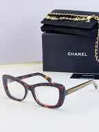 Tortoiseshell glasses with oversized square frames, clear lenses, and gold chain temples