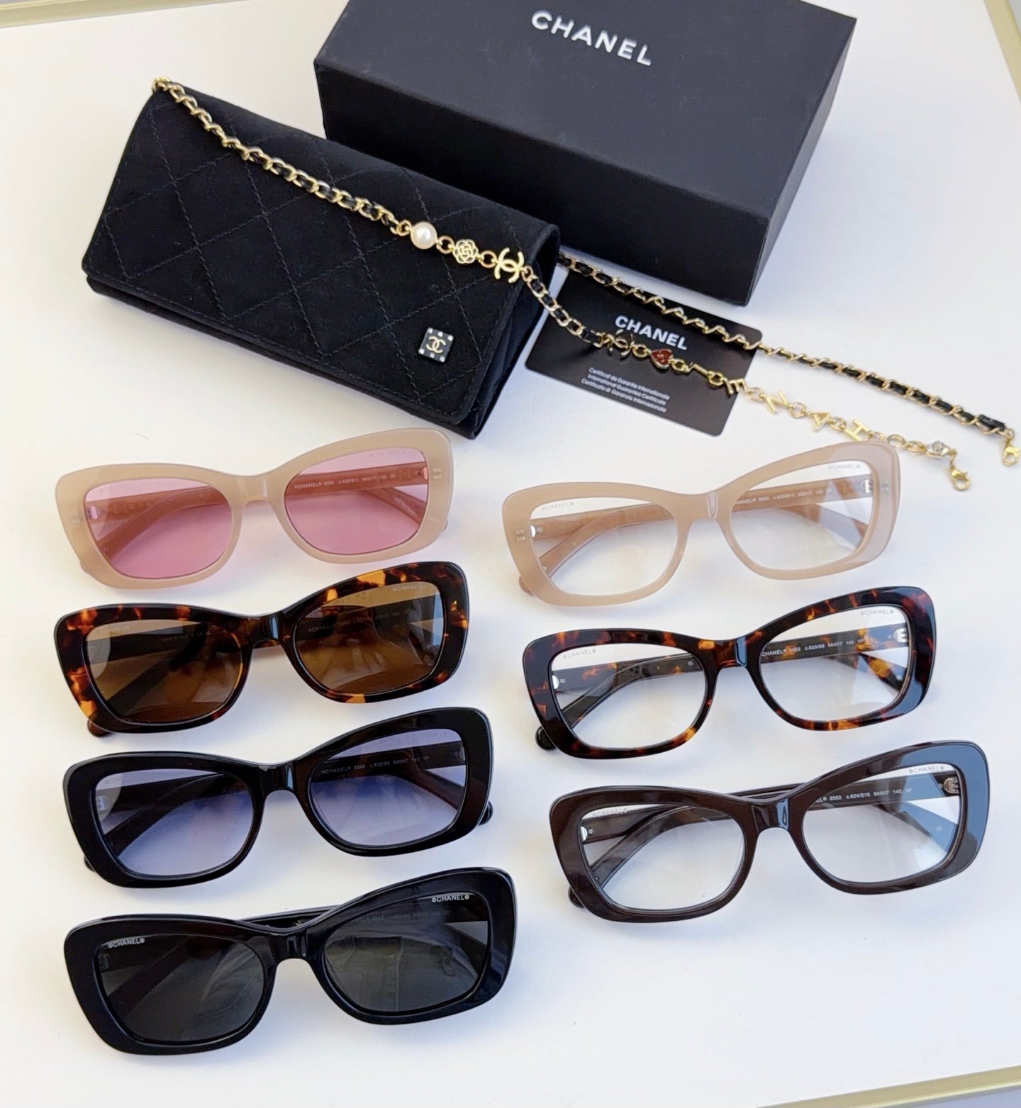 Assorted eyeglasses and sunglasses with various frames, tinted lenses, and gold chain details