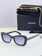 Blue-gray glasses with cat-eye oval frames and gold chain detail on the temples