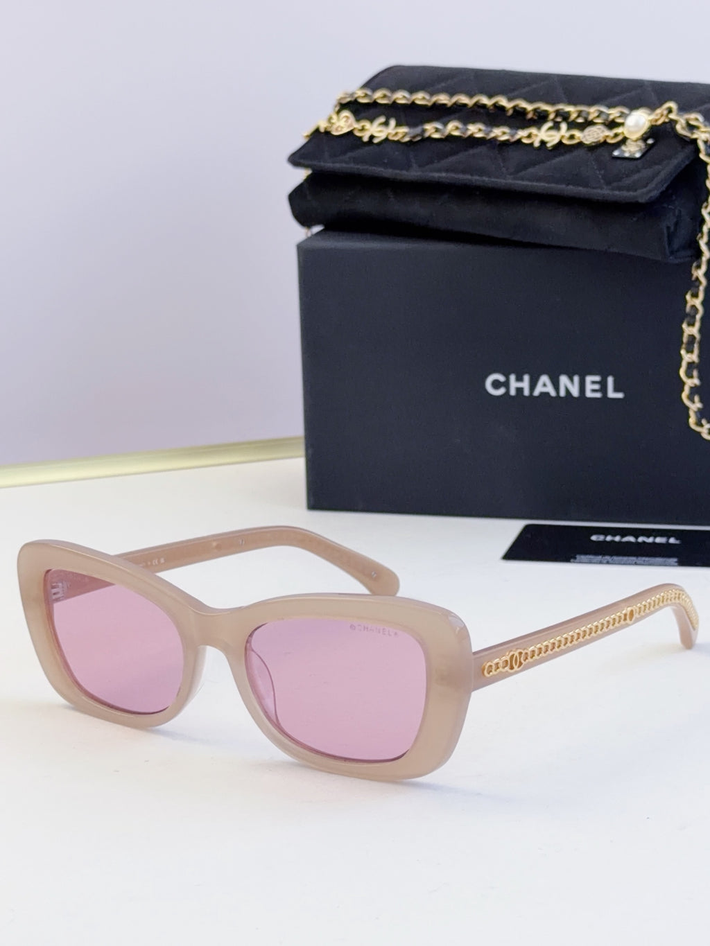 Light tan glasses with oversized square frames and pink tinted lenses