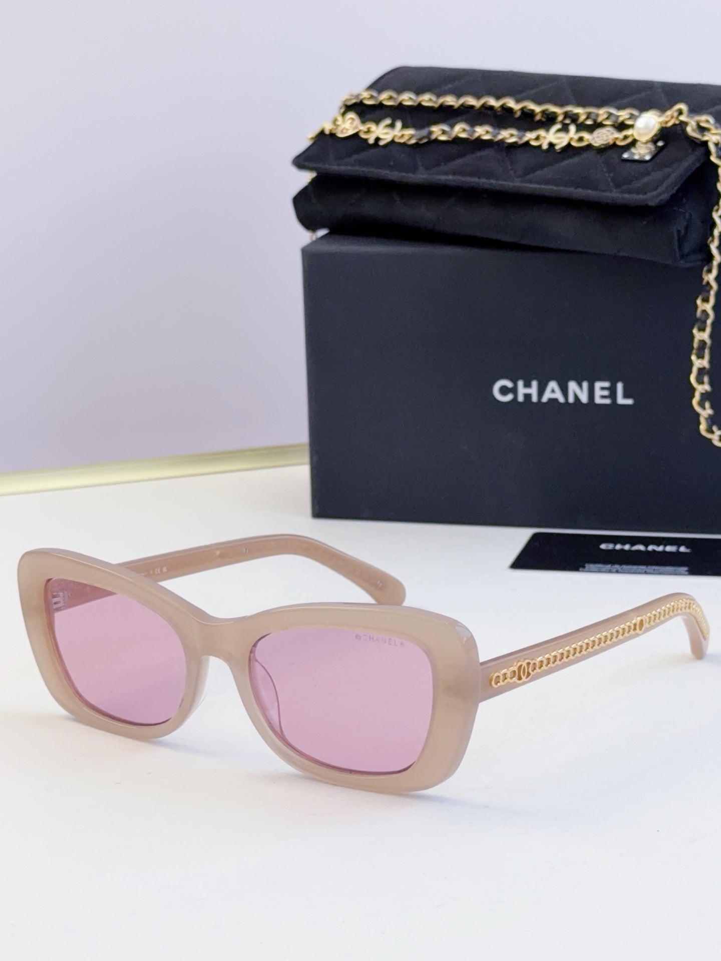 Light tan glasses with oversized square frames and pink tinted lenses