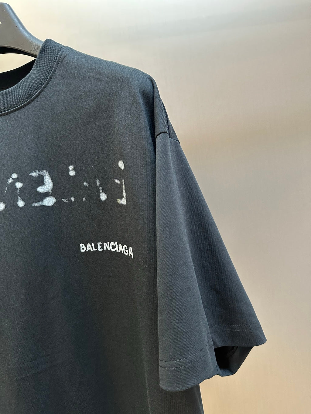 Balenciaga T-shirt sleeve and chest BALENCIAGA print on dark gray fabric.