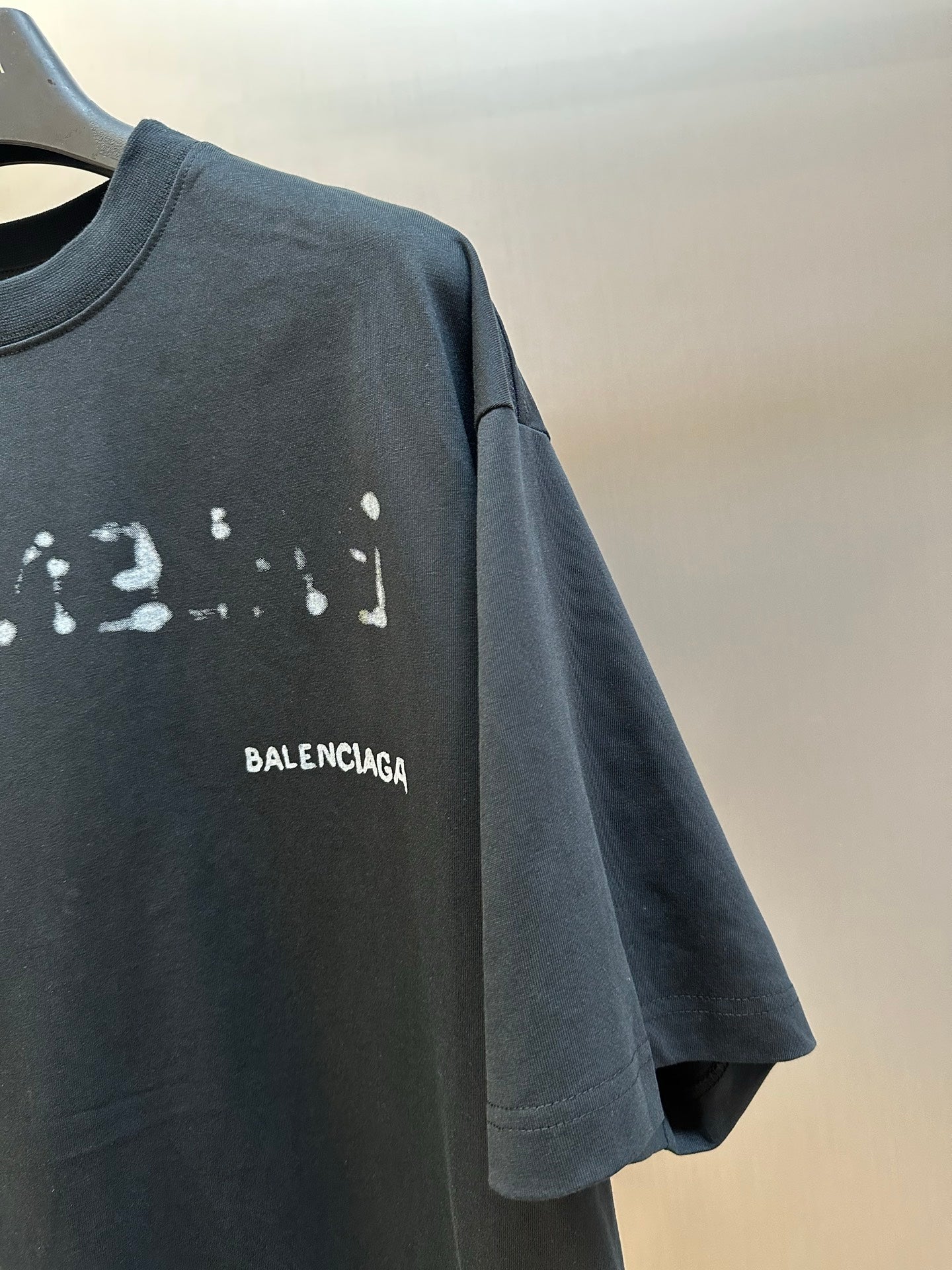Balenciaga T-shirt sleeve and chest BALENCIAGA print on dark gray fabric.