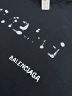 Balenciaga T-shirt fabric close-up with splatter print and BALENCIAGA text in white.
