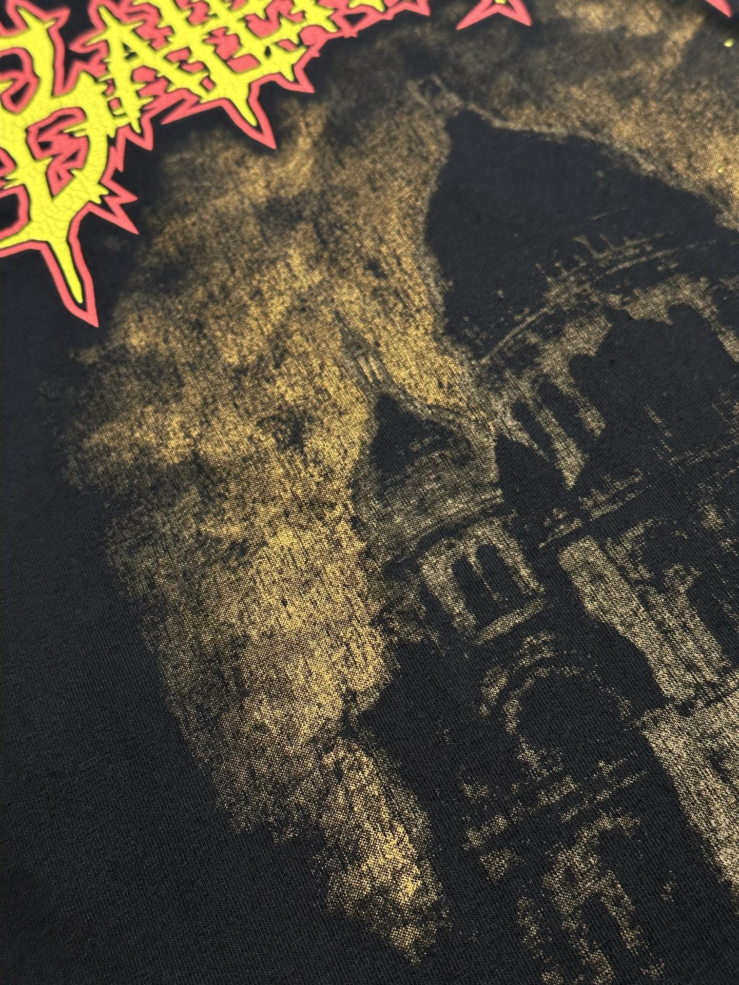 Dark T-shirt close-up of gold-toned building graphic and neon edge