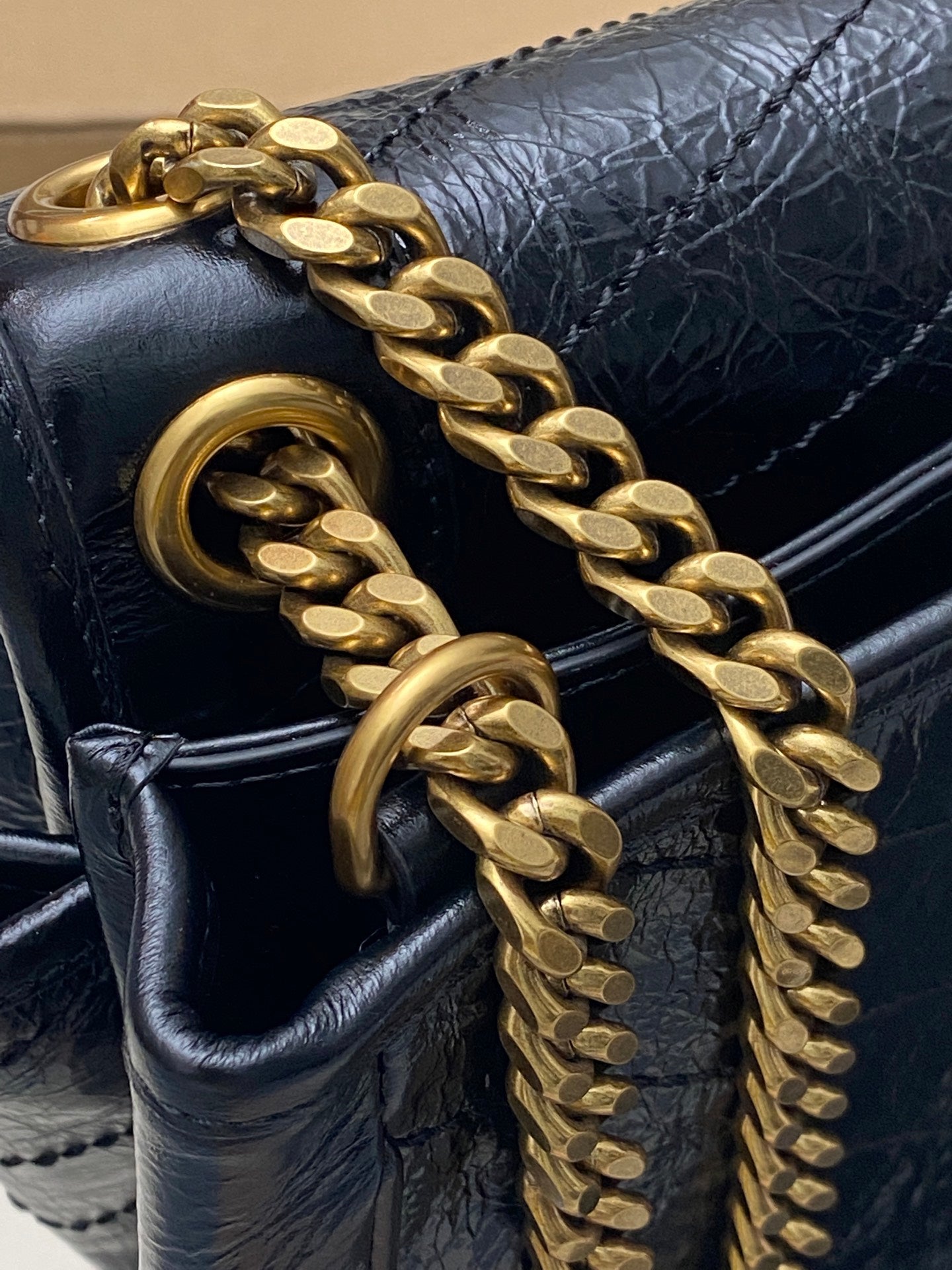 YSL chain strap detail on dark blue leather bag, gold hardware link accents