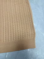 Beige knit polo shirt hem with vertical ribbed cable pattern.