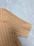 Beige cable-knit polo shirt sleeve with ribbed cuff.