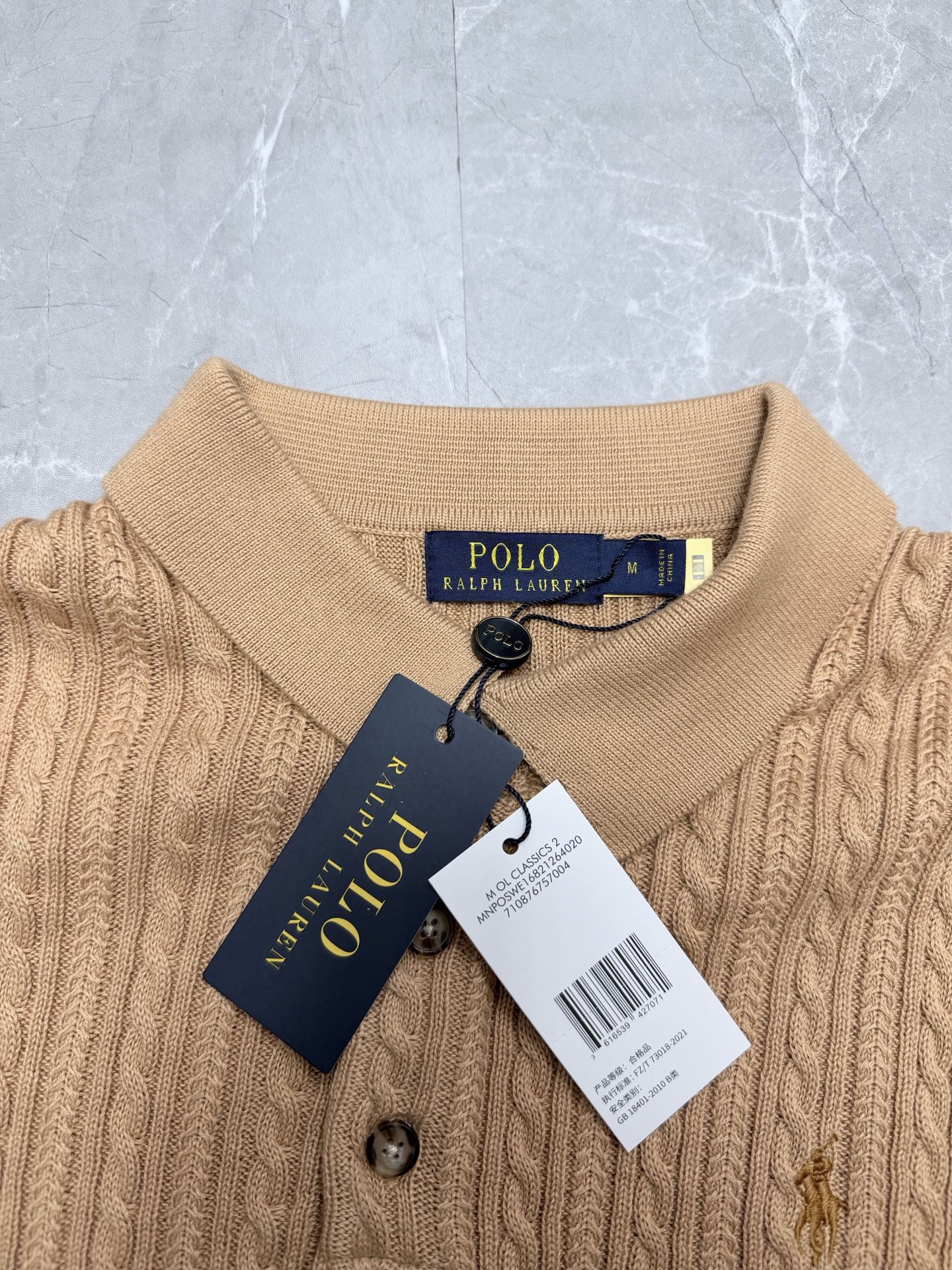 Beige knit polo shirt neckline with button placket and attached Polo Ralph Lauren tag.