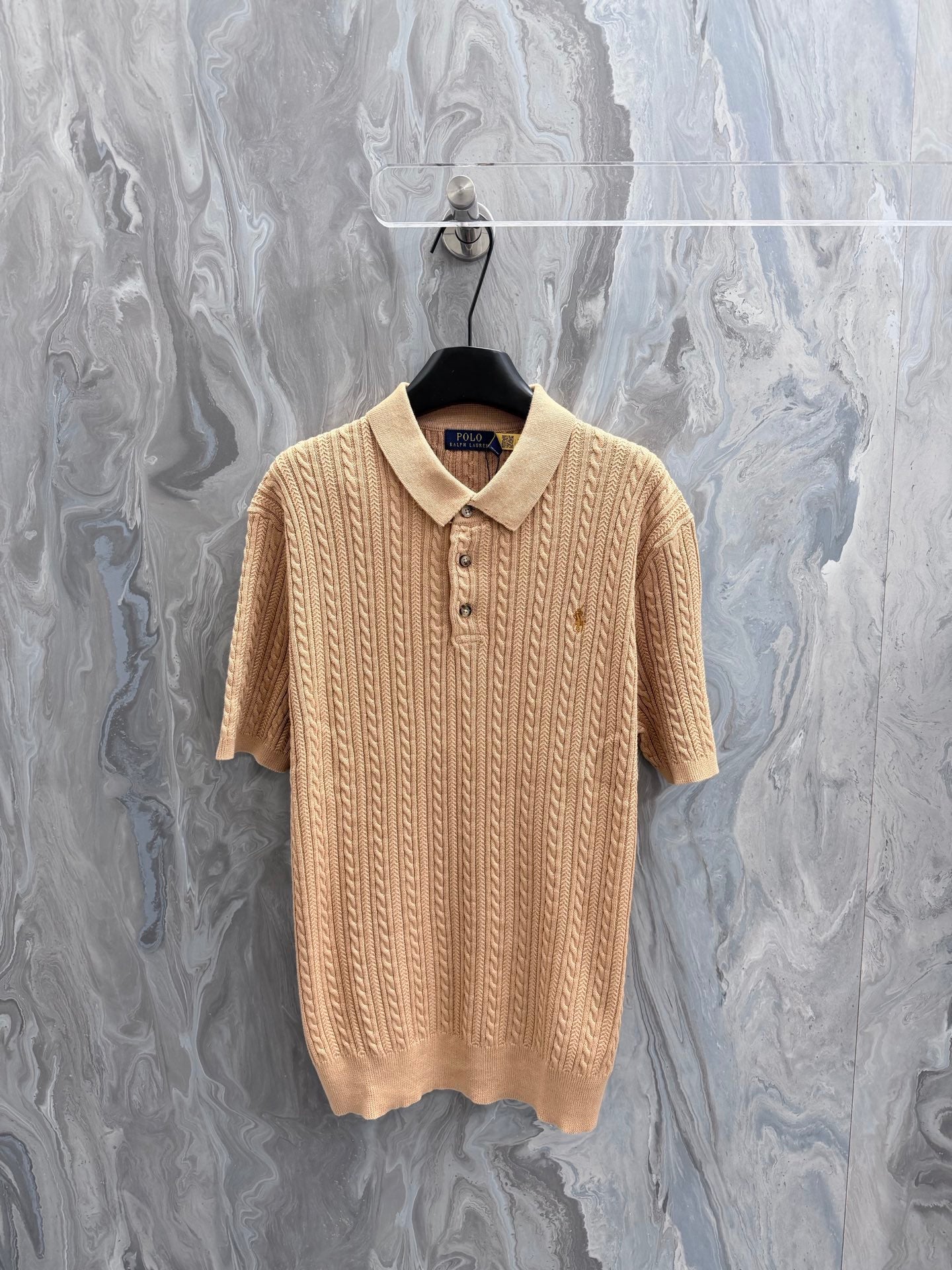 Beige knit polo shirt with ribbed collar and button placket, short sleeves.