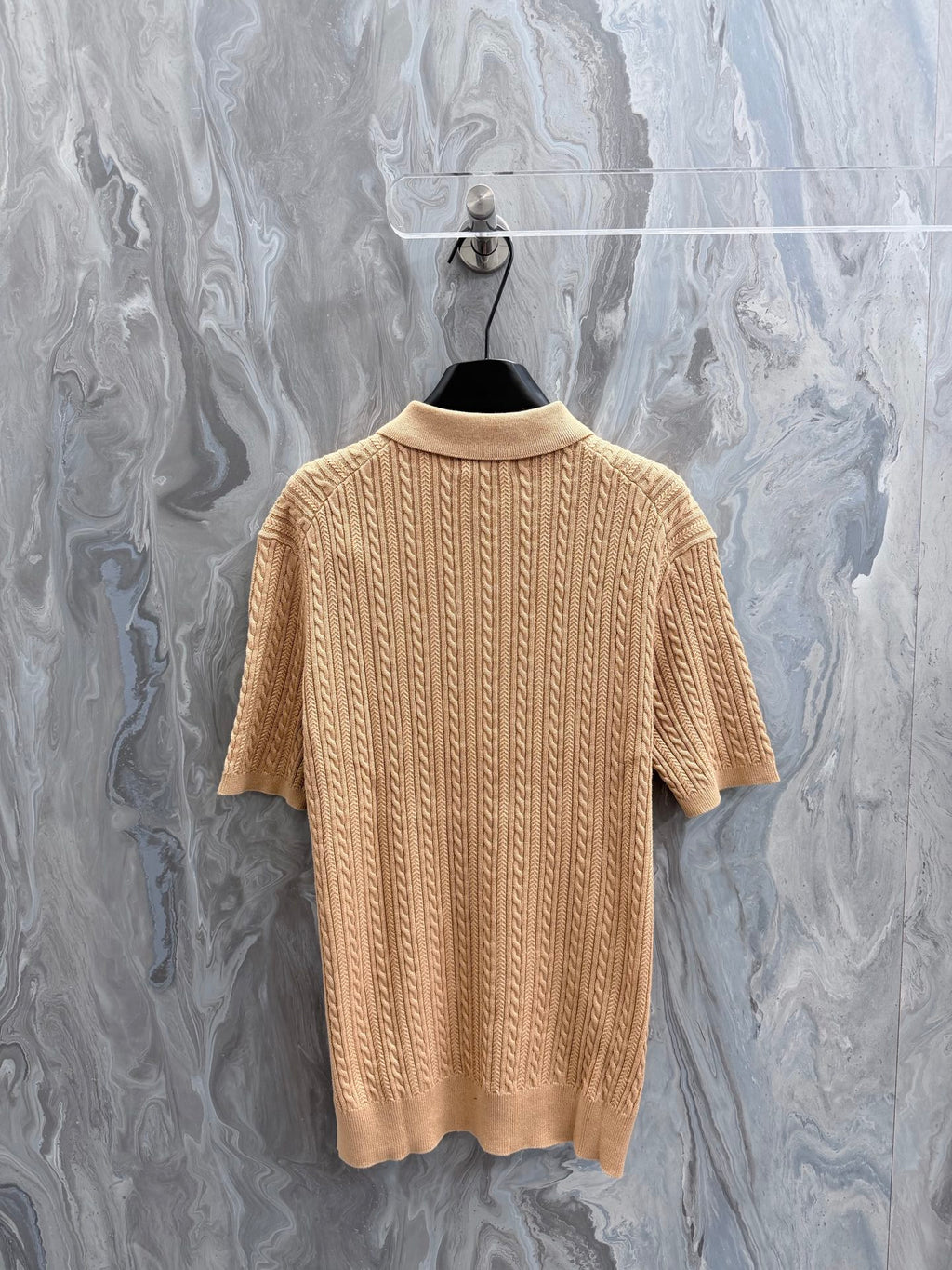 Beige knit polo shirt with ribbed crew collar and vertical cable texture, short sleeves.