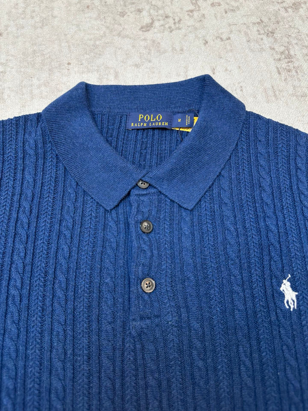 Blue cable-knit polo shirt with embroidered polo player logo and buttoned collar
