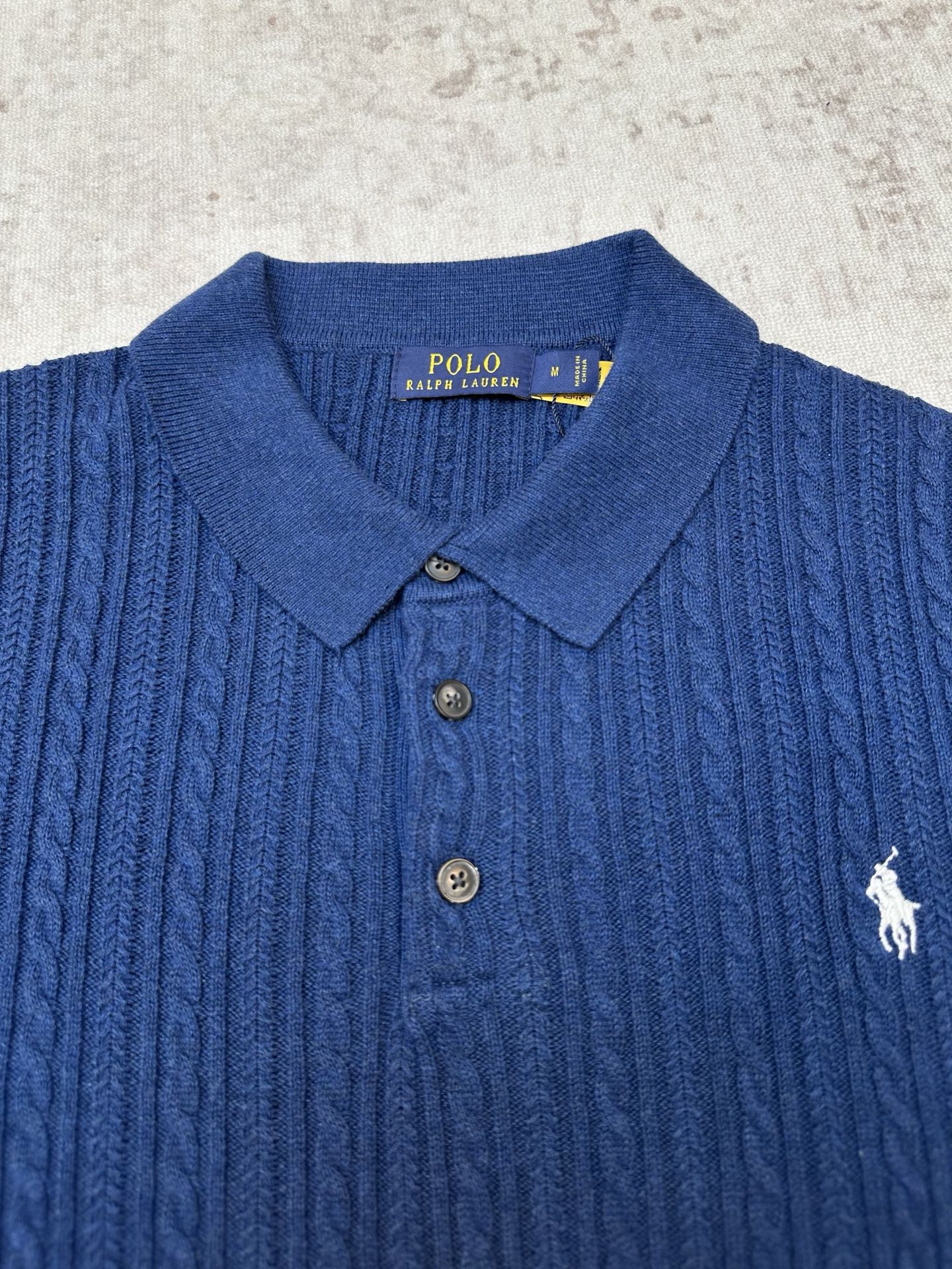 Blue cable-knit polo shirt with embroidered polo player logo and buttoned collar