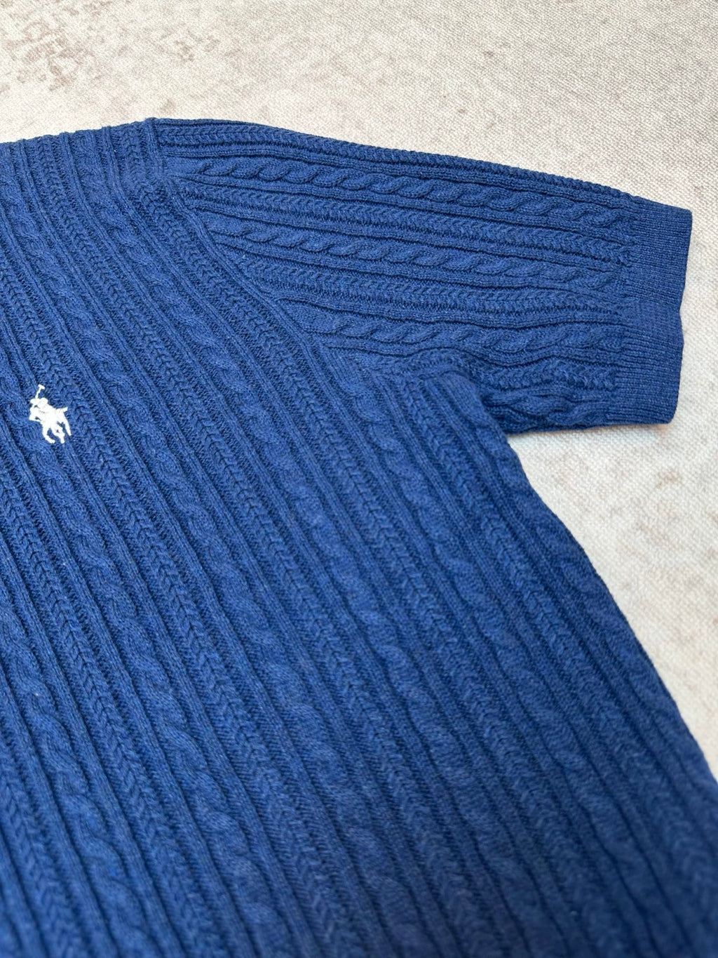 Blue cable-knit polo shirt sleeve cuff and knit texture detail